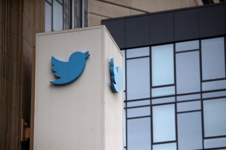 A Twitter logo outside a glass building.